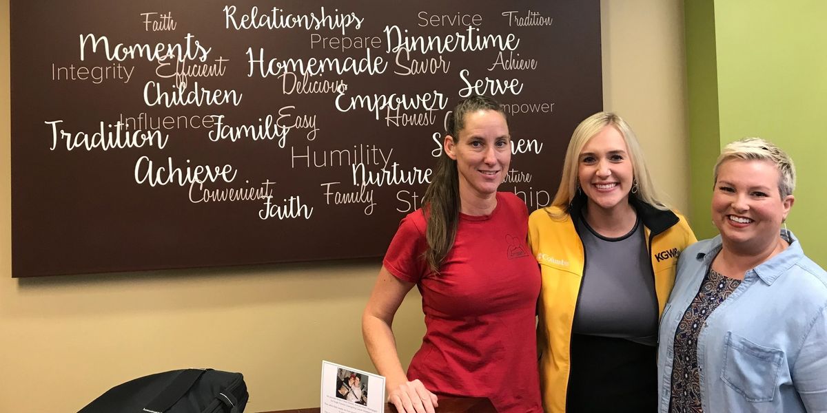 Three women smiling in front of word art.