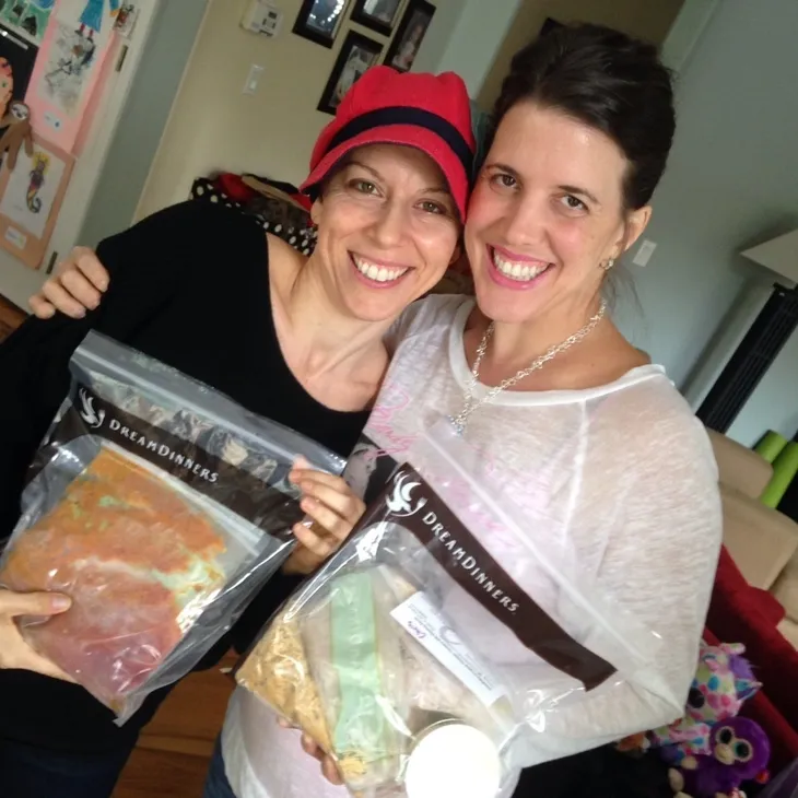 Two women smiling holding meal bags.