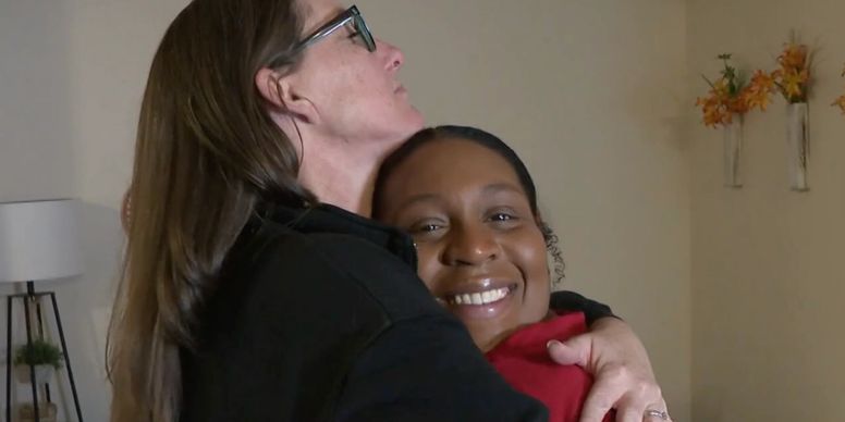 Smiling woman embraced by another