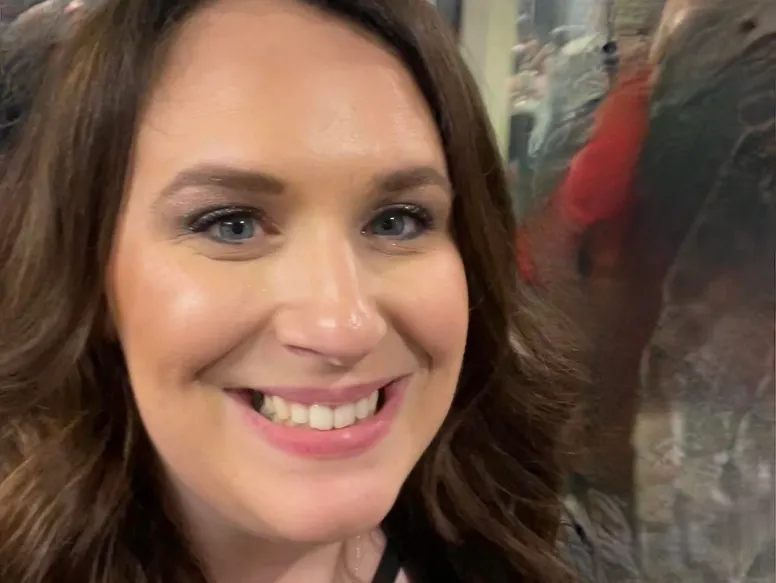 Woman smiling indoors with others nearby