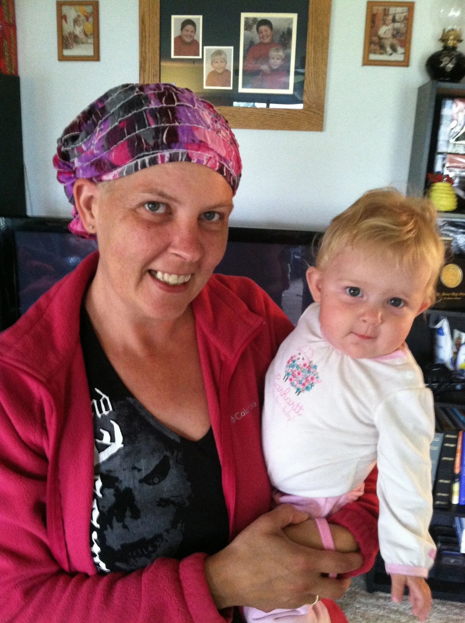 A woman in a pink headscarf holding a baby with blonde hair.