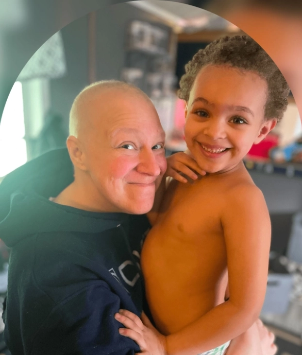 A joyful moment between a bald adult and a smiling child indoors.