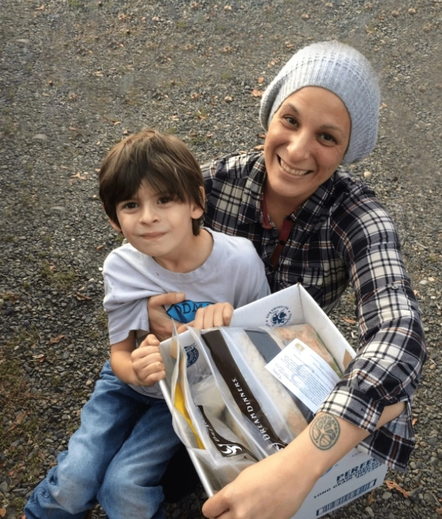 A woman and child happily holding a clear bag outdoors.