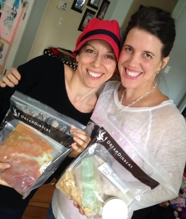 Two smiling women holding bags of frozen food.